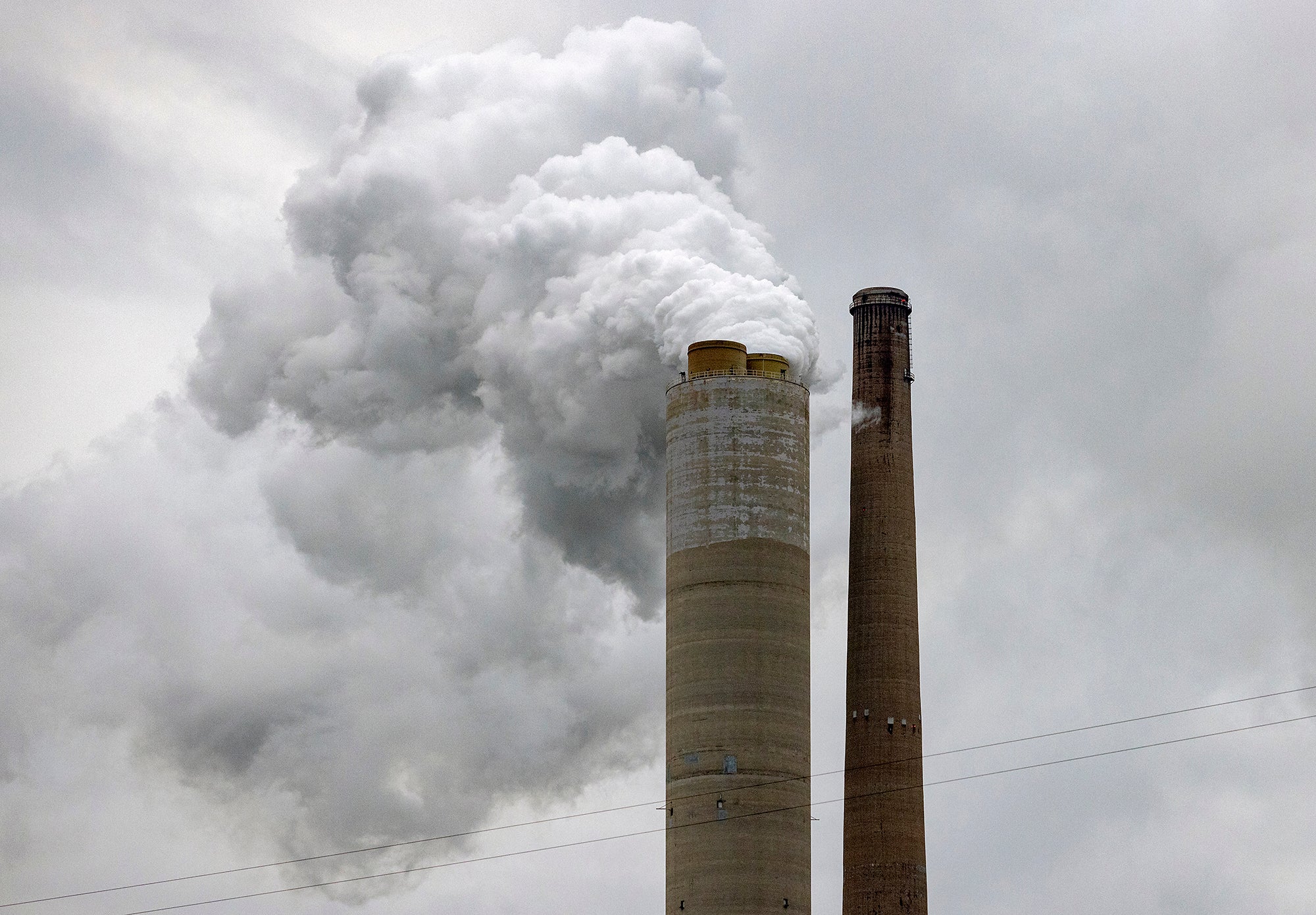 Coal pollution Two smoke stacks against a gray sky. One is releasing a lot of white smoke.