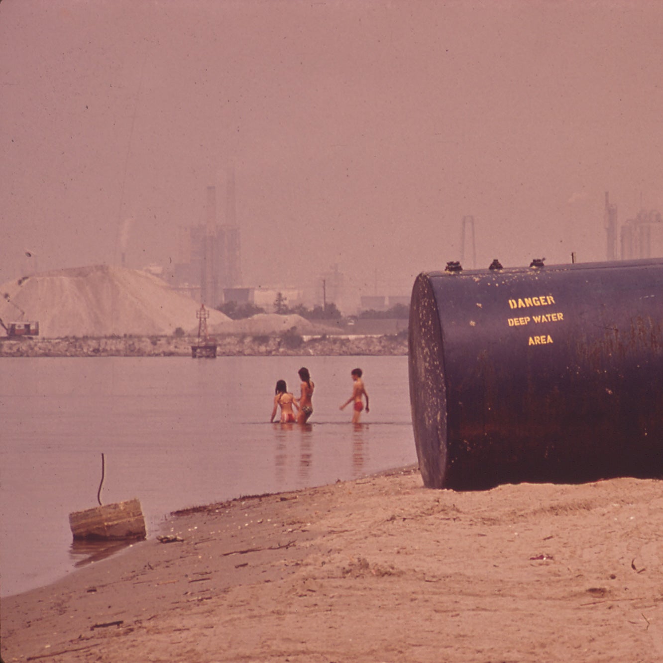 People play in the waters of Lake Charles, Louisiana, as chemical plants loom in the background in June 1972